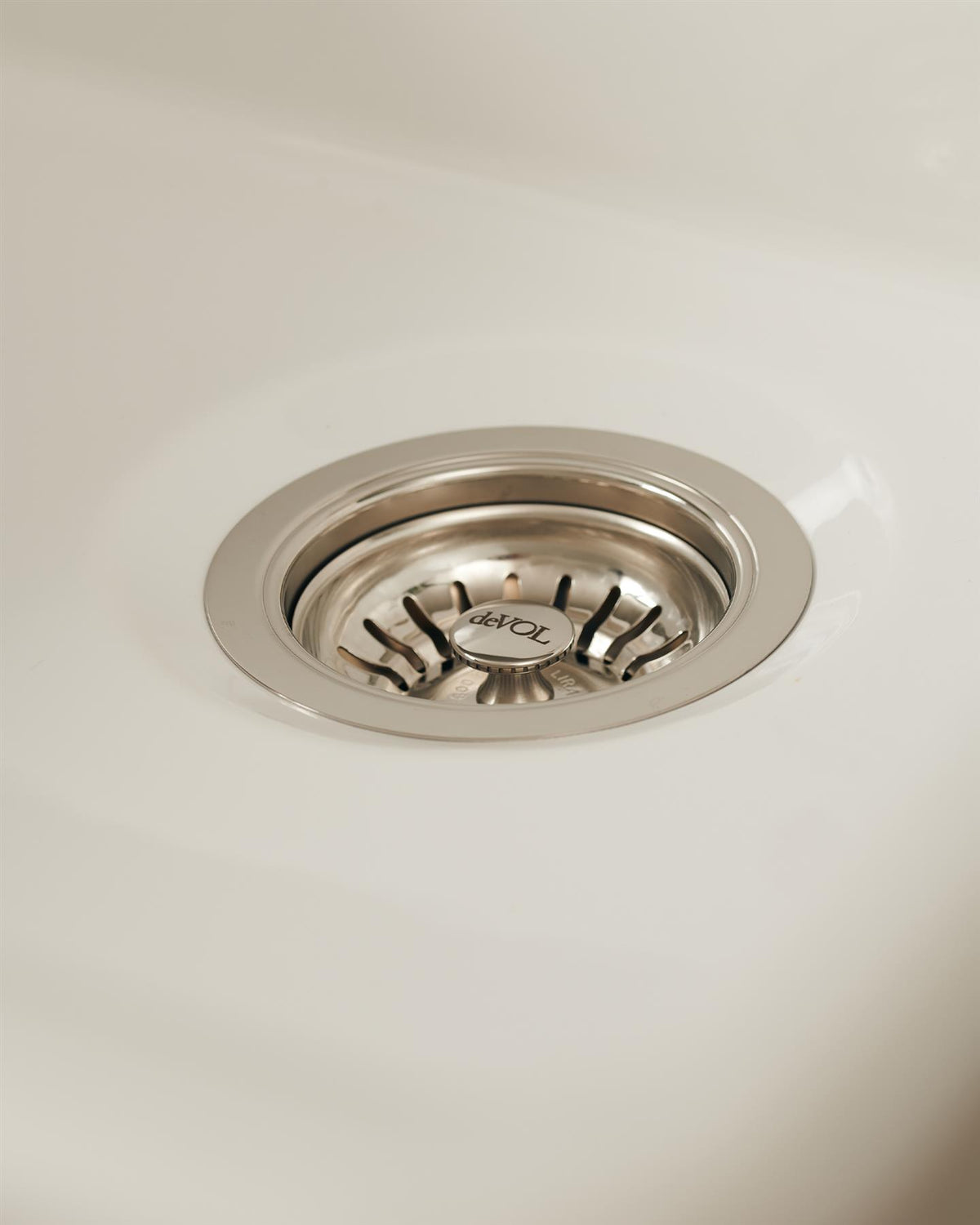 A basket waste strainer in a polished chrome finish fitted in a ceramic sink. TEST