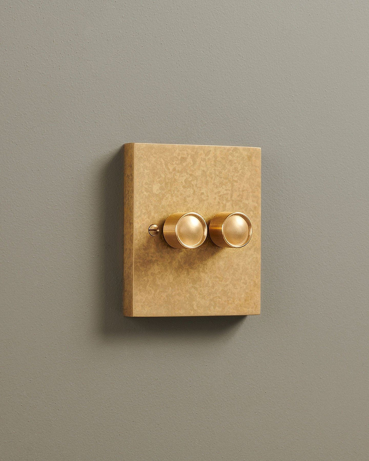 An oblique view of a 2 gang box dimmer switch in a mottled aged brass finish. TEST