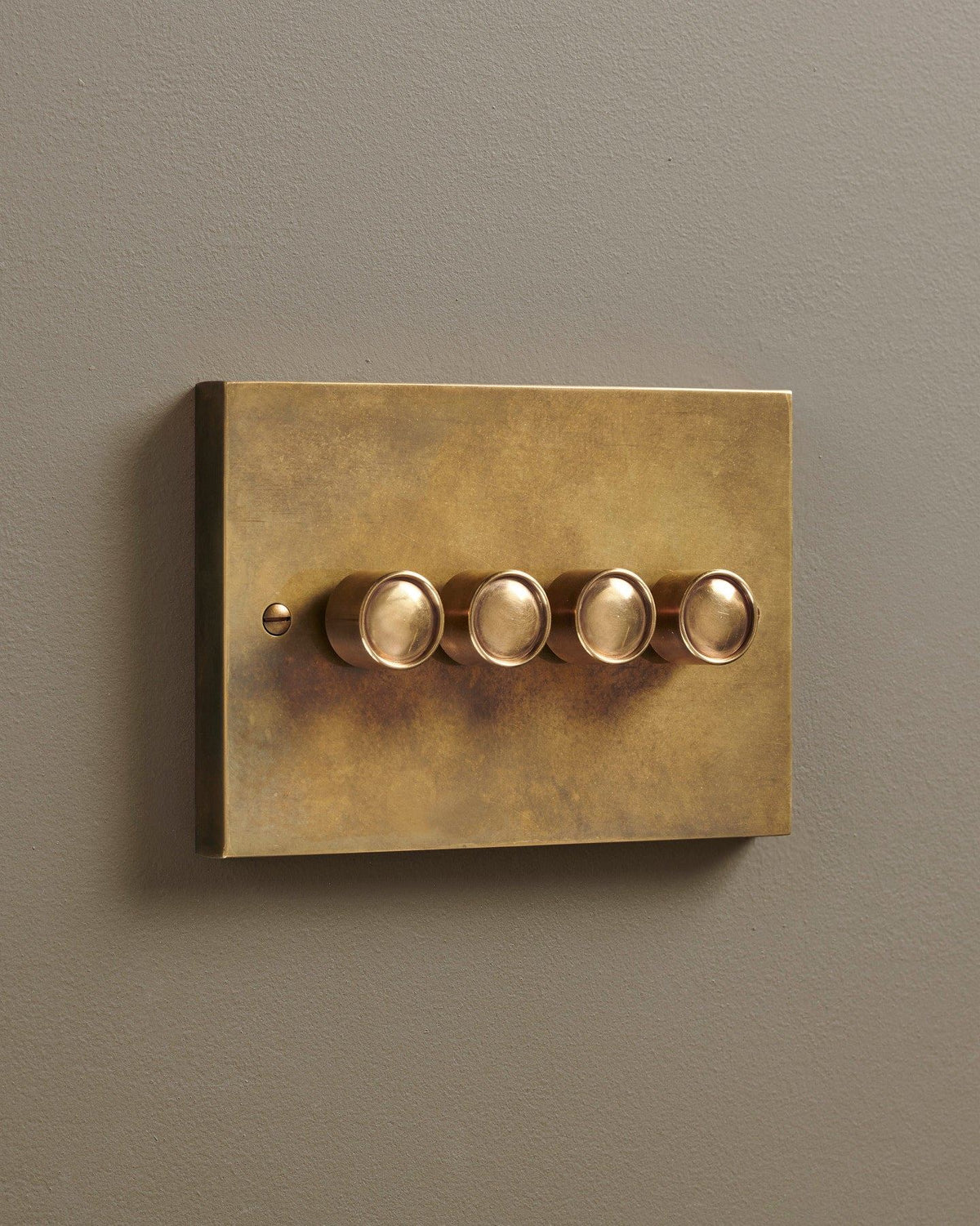 An oblique view of a 4 gang box dimmer switch in a warm burnished brass finish. TEST