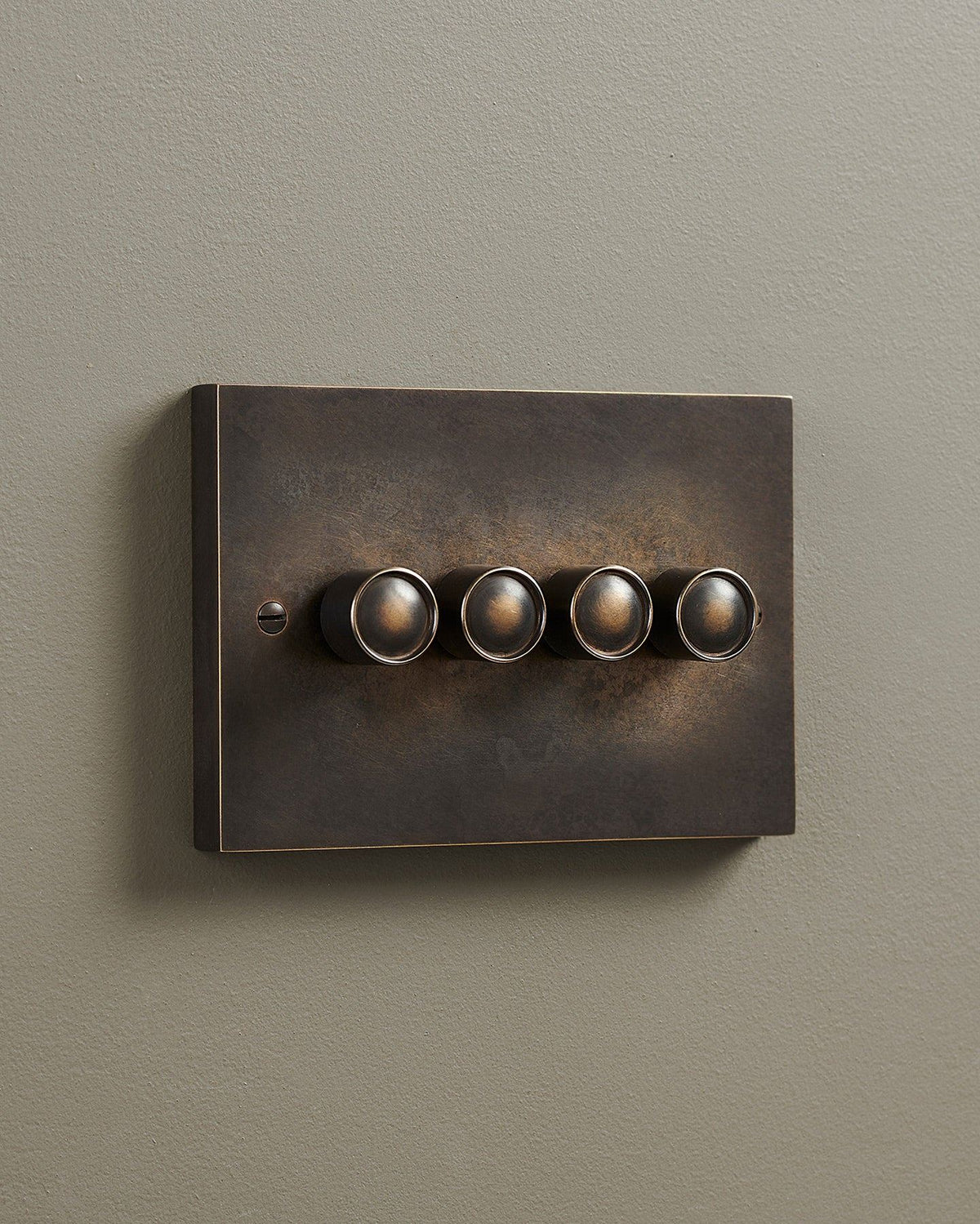 An oblique view of a 4 gang box dimmer switch in a dark oxidised brass finish. TEST
