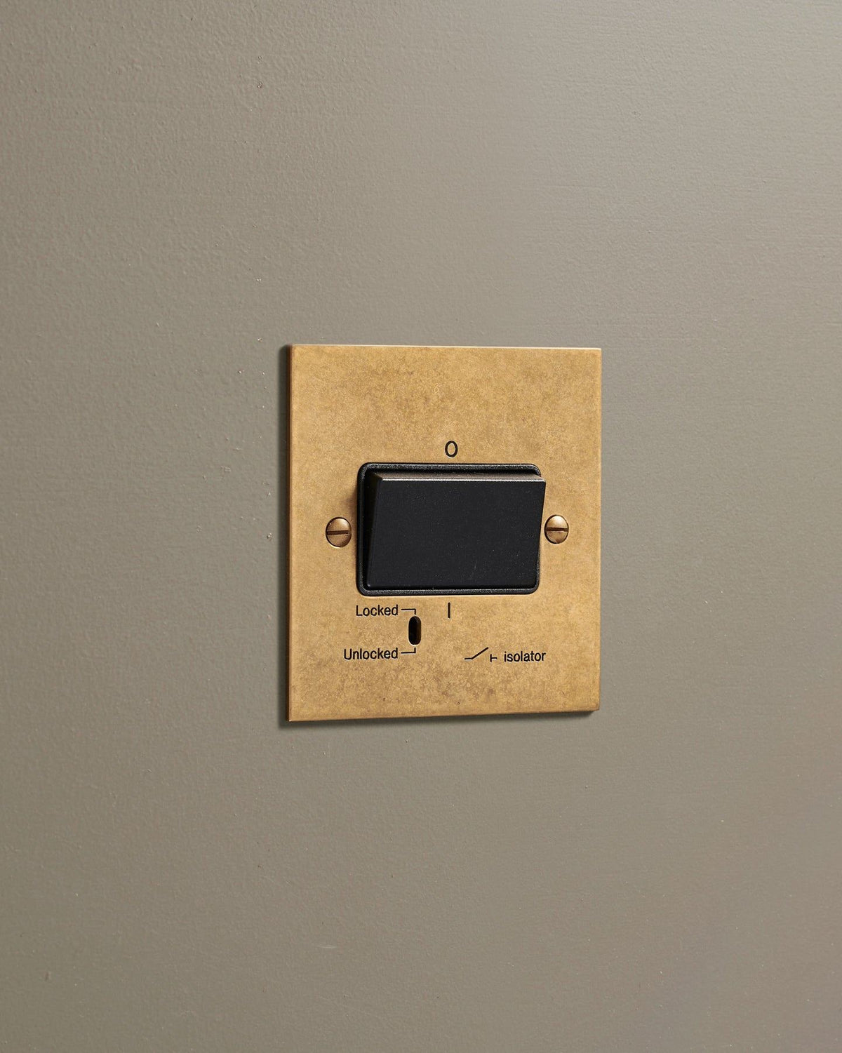 An oblique view of a classic extractor fan isolator switch in a mottled aged brass finish. TEST