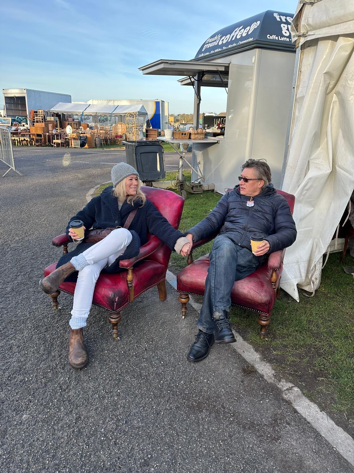 Helen Parker and Paul O'Leary sitting in antique leather chairs at an outdoor antiques market