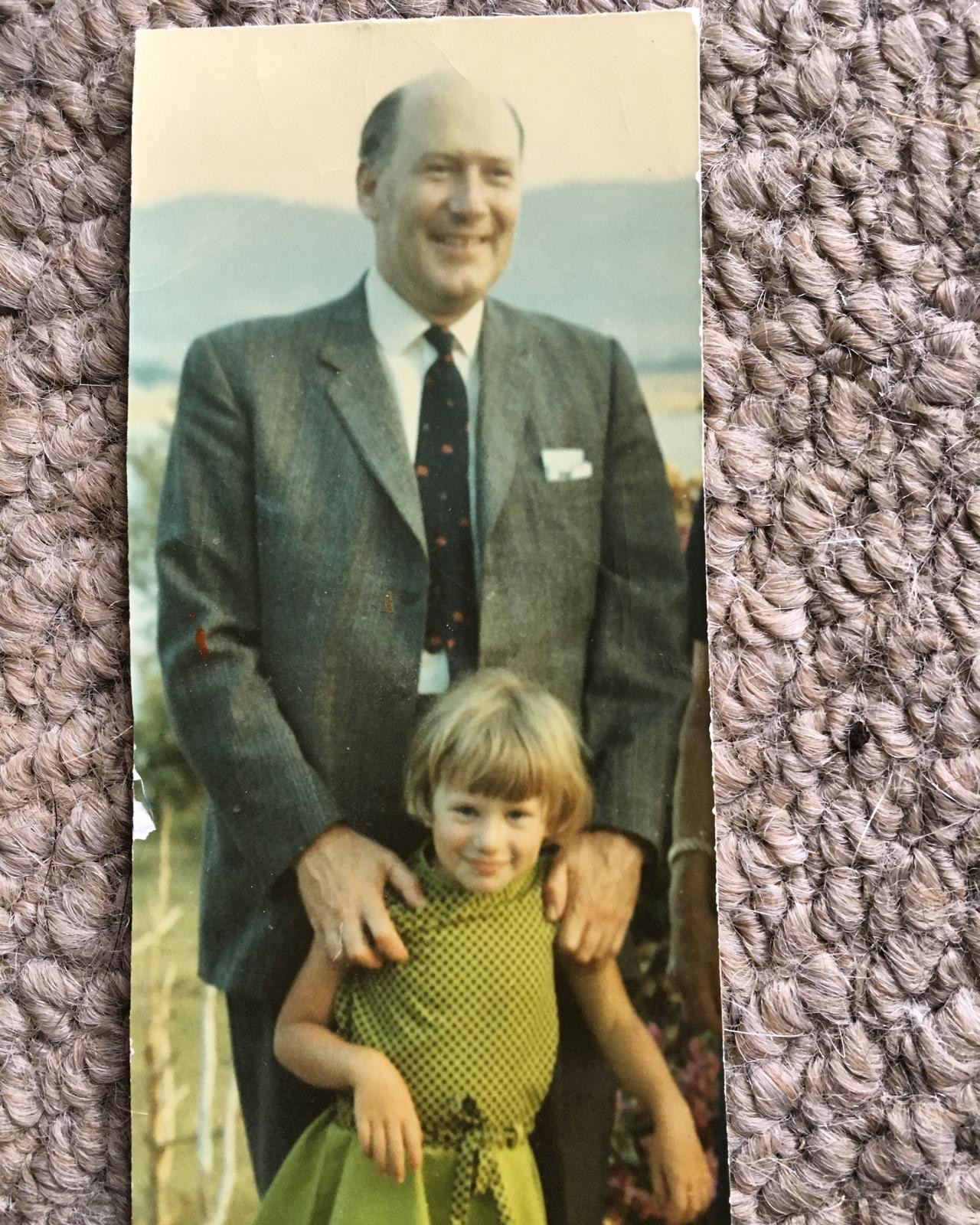 A photo of a photograph, it shows a young girl with her father behind wearing a suit.