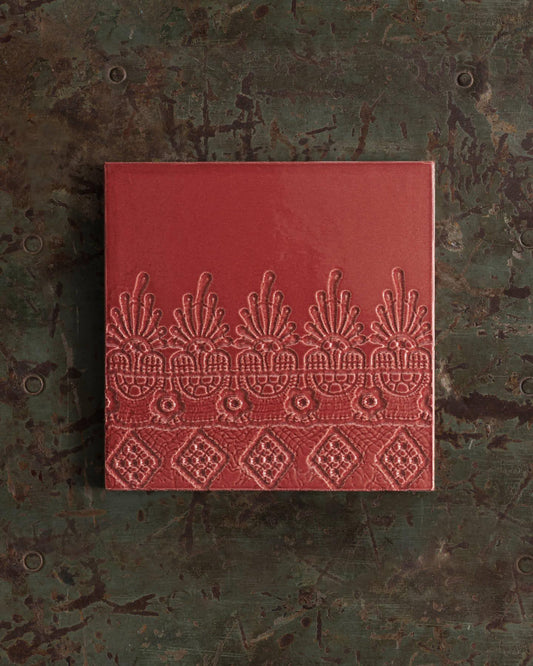 Red embossed book on a textured green surface. | Flanders Square