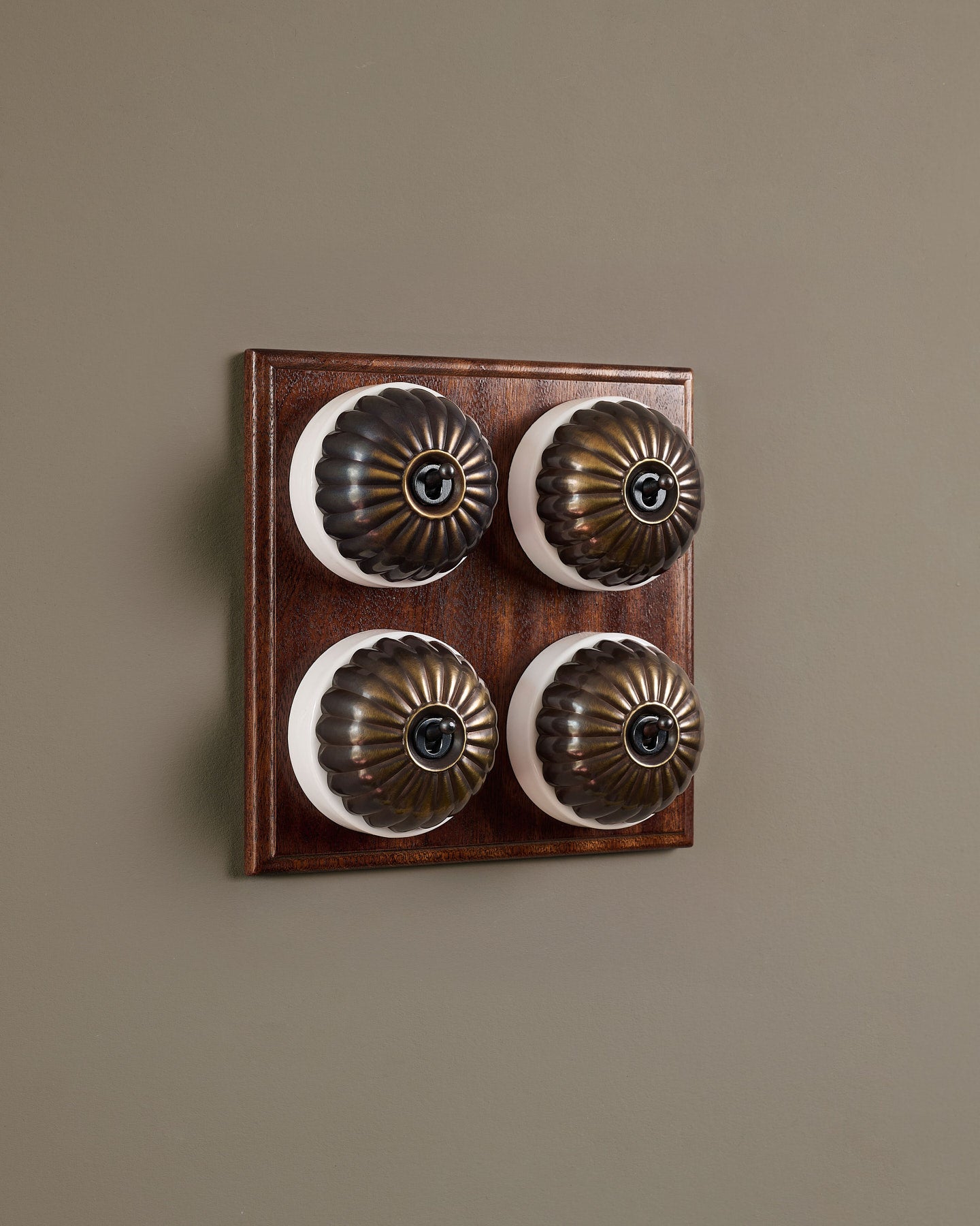The Jelly Toggle Switch (4 Gang Bank & Mahogany Finish Pattress) - Oxidised Brass with White Base.