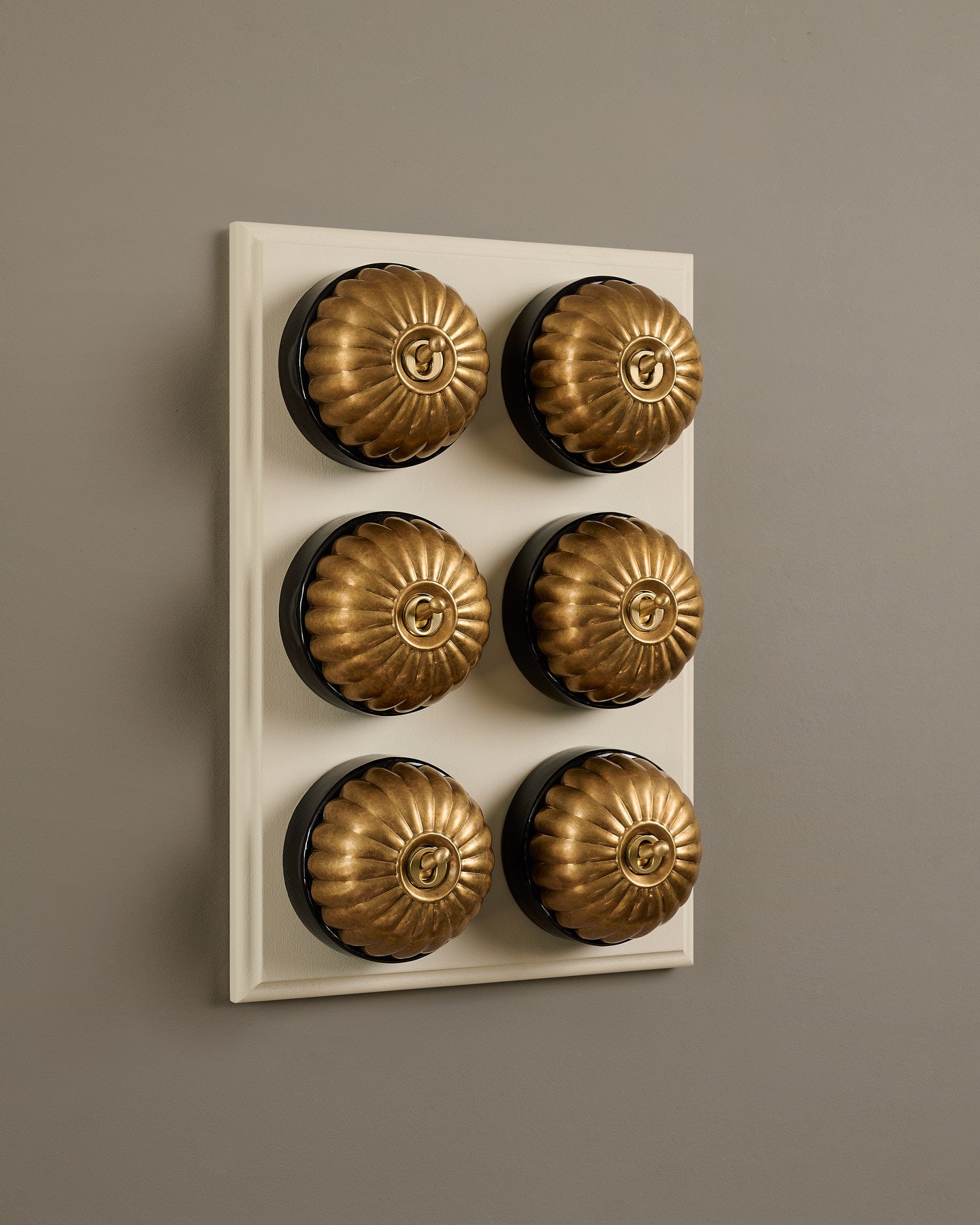 The Jelly Toggle Switch (6 Gang & Primed Maple Pattress) - Aged Brass with Black Base.