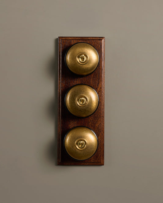 The Dolly Toggle Switch (3 Gang & Mahogany Finish Pattress) - Aged Brass with Black Base.