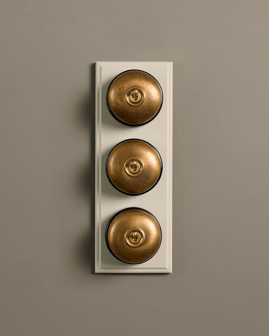 The Dolly Toggle Switch (3 Gang & Primed Maple Pattress) - Aged Brass with Black Base.