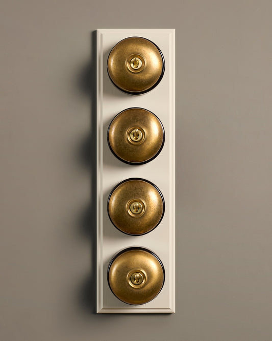 The Dolly Toggle Switch (4 Gang Row & Primed Maple Pattress) - Aged Brass with Black Base.