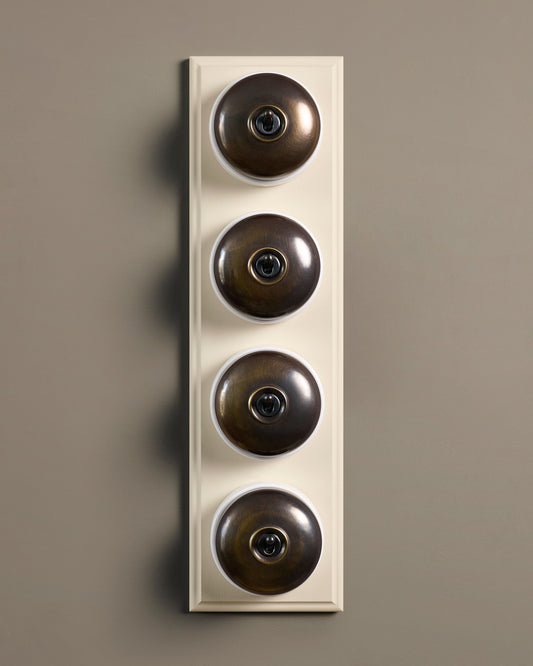 The Dolly Toggle Switch (4 Gang Row & Primed Maple Pattress) - Oxidised Brass with White Base.