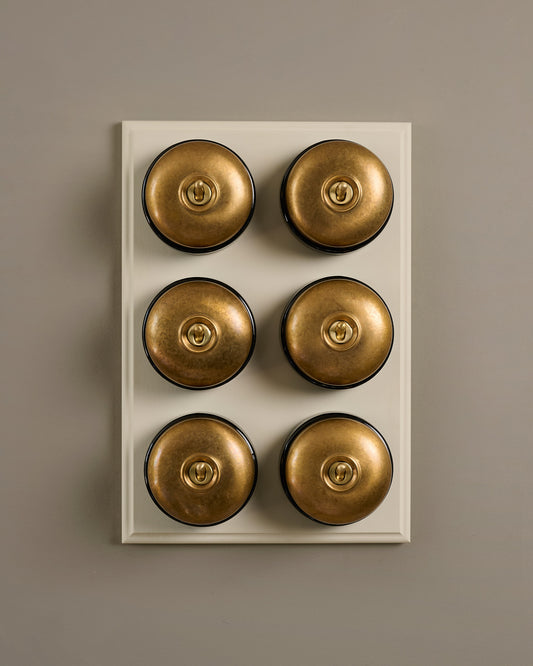 The Dolly Toggle Switch (6 Gang & Primed Maple Pattress) - Aged Brass with Black Base.