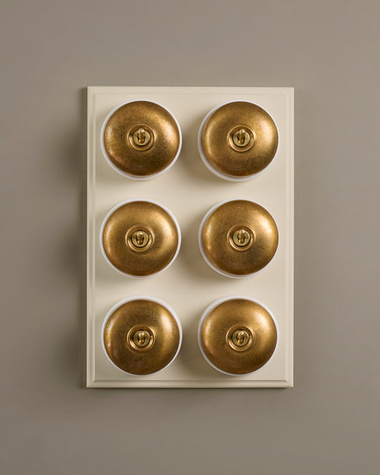The Dolly Toggle Switch (6 Gang & Primed Maple Pattress) - Aged Brass with White Base.