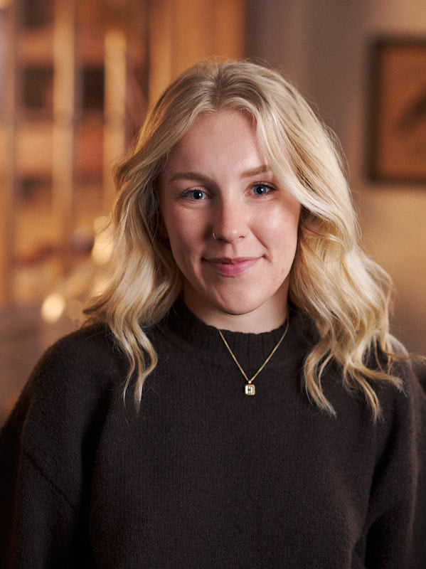 Woman with blonde hair wearing a dark sweater indoors