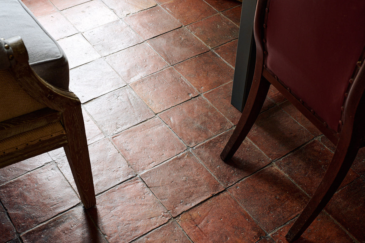 A close and oblique view of an antique beeswax treated terracotta square tiled floor.