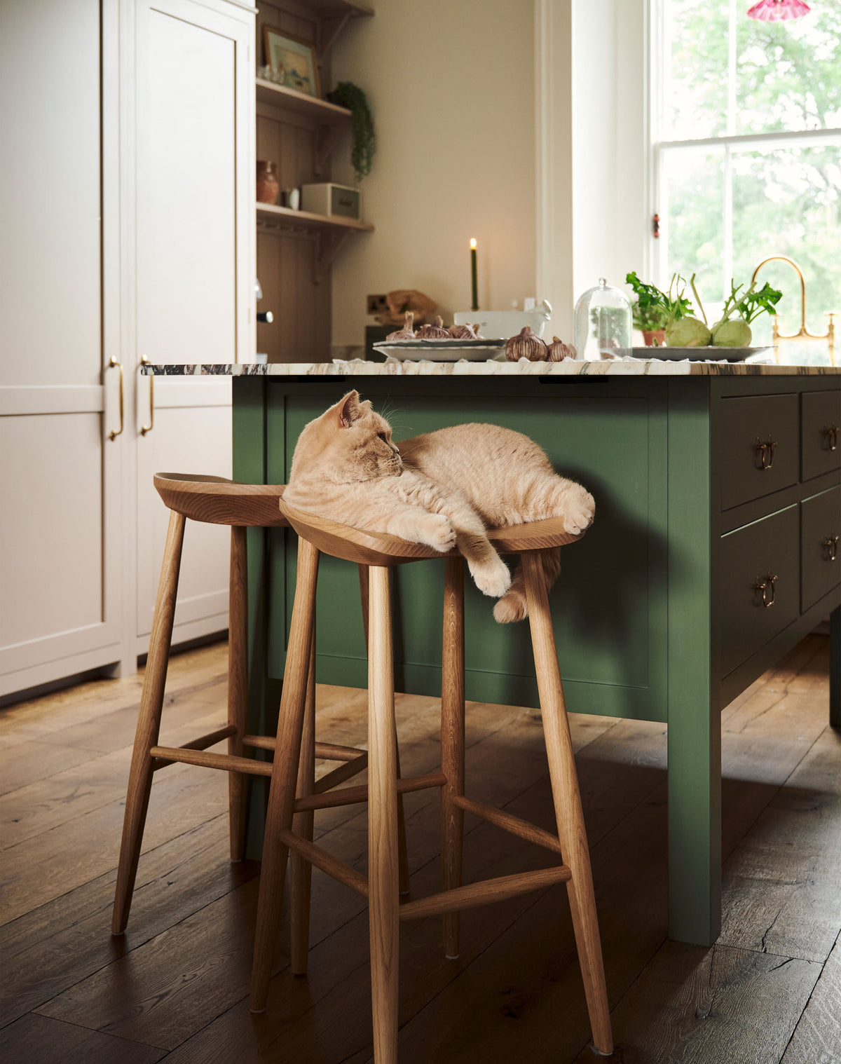 At the edge of a breakfast nook is a pair of deVOL bum stool with an adorable cat perched on one of the stools.