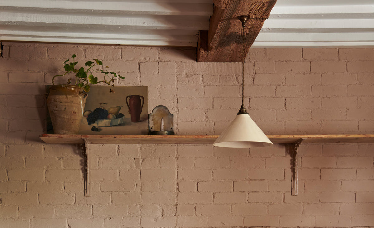 A close look at the creamware pendant light hanging beautifully on the wooden beam of a 16th century building.