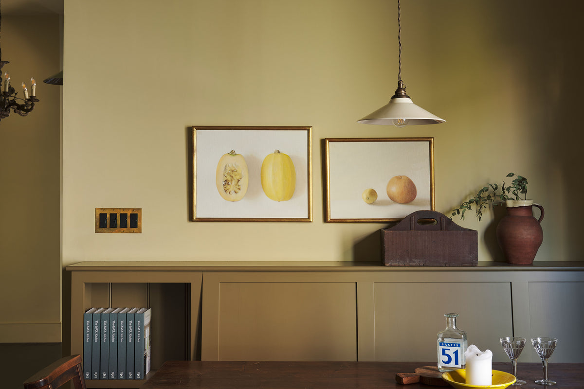 Heirloom brass switches in a yellow room with a glimpse of cupboard showing the deVOL hardback book.
