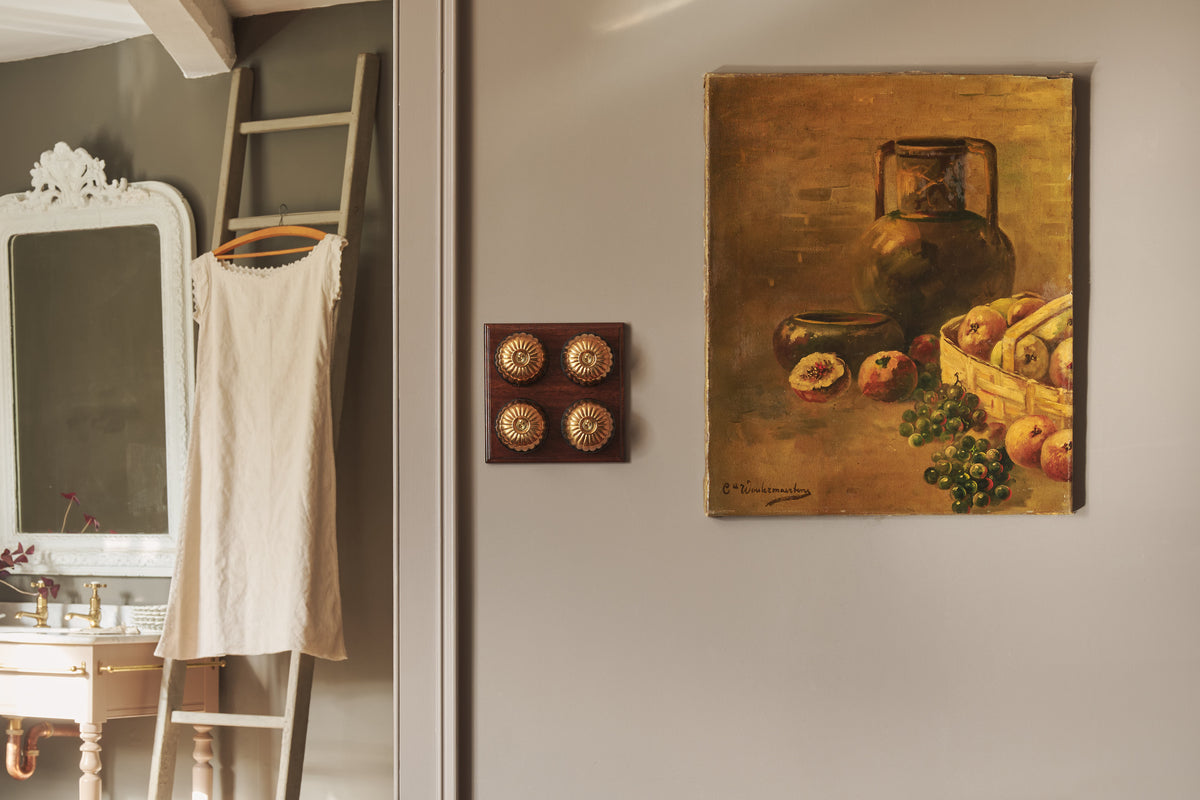 A four gang Jelly Toggle Switch in an Heirloom Brass finish, with a Mahogany Finish wooden pattress, fitted by an open doorway with an oil painting and vintage styling in the background.