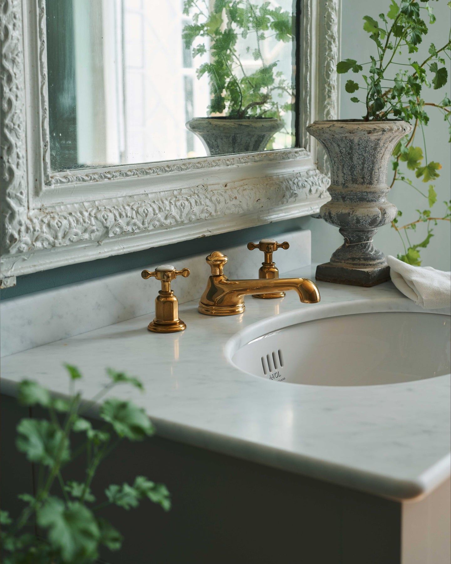 An oblique view of an aged brass mixer tap for a bathroom basin sink fitted to a mushroom painted washstand.