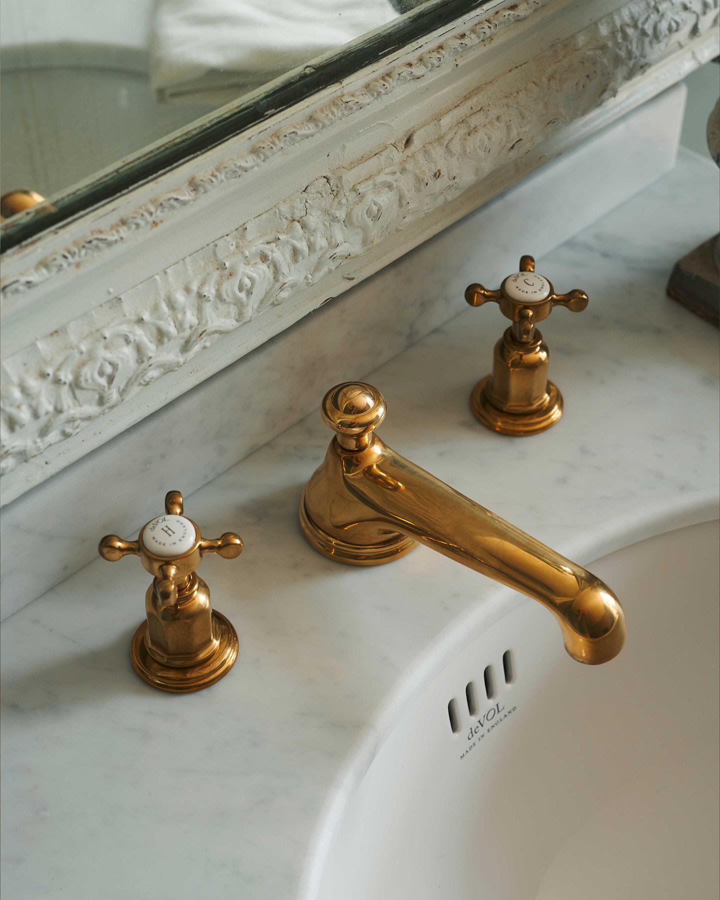 A close-up oblique view of an aged brass mixer tap for a bathroom basin sink.