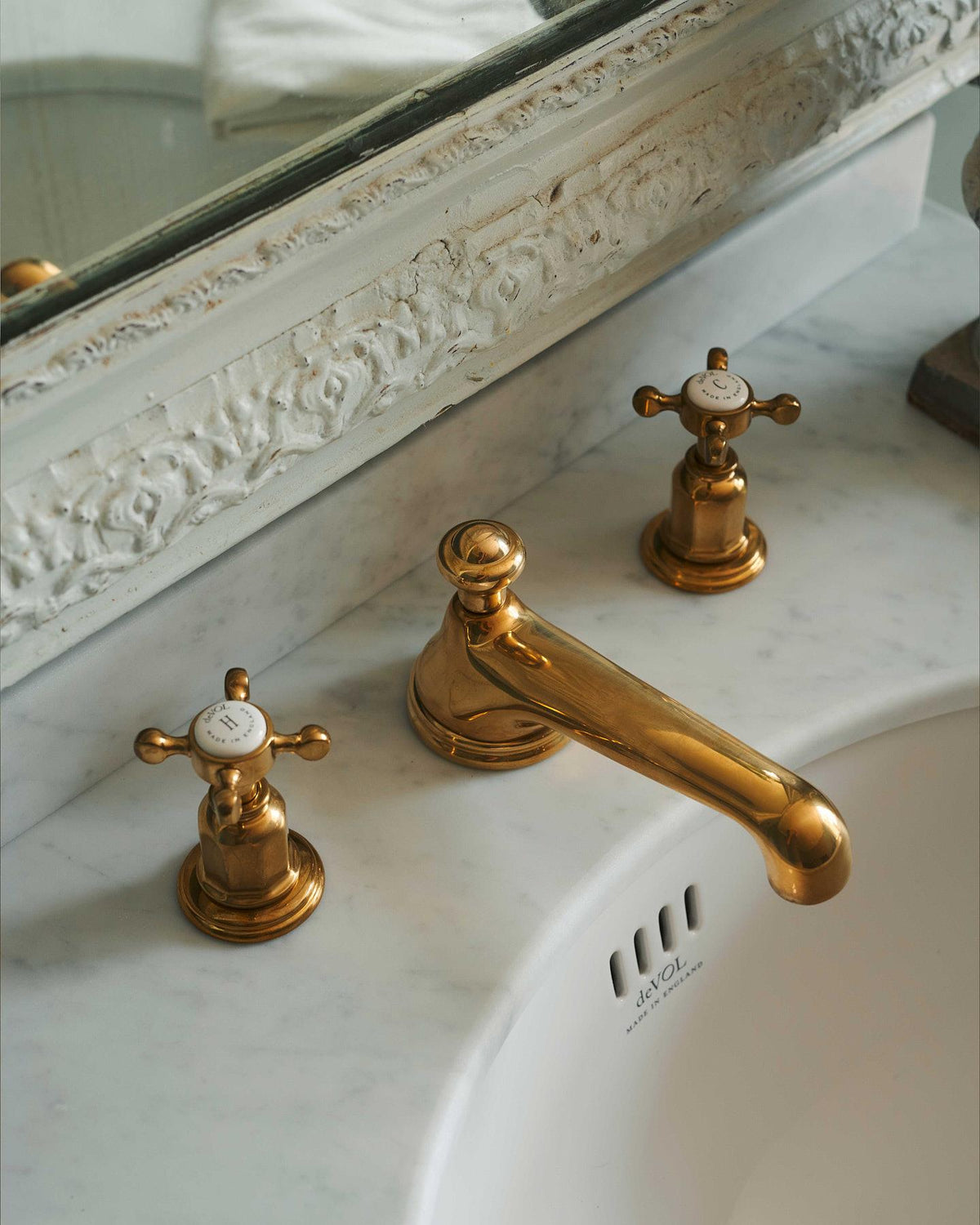 A close-up oblique view of an aged brass mixer tap for a bathroom basin sink. TEST