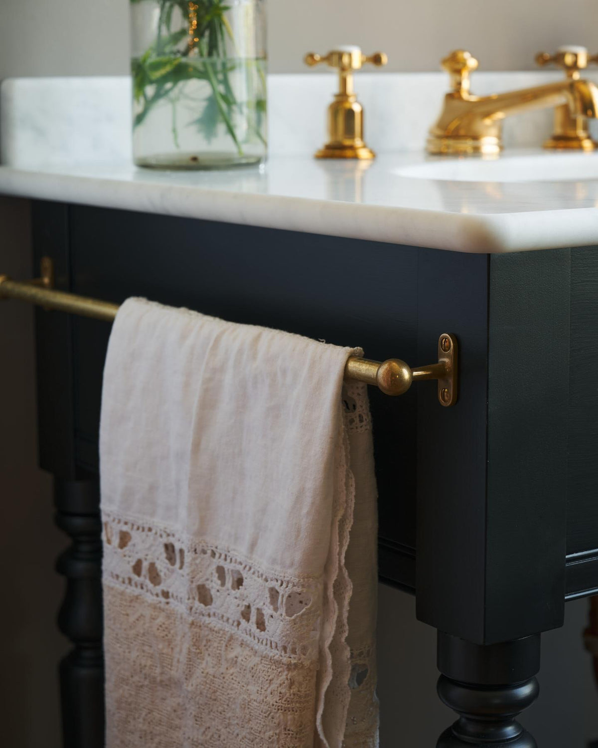 A detailed view of an aged brass towel rail attached to the left side of a Victorian-inspired washstand, a vintage lace hand towel hangs from the rail. | Left Towel Rail shown TEST