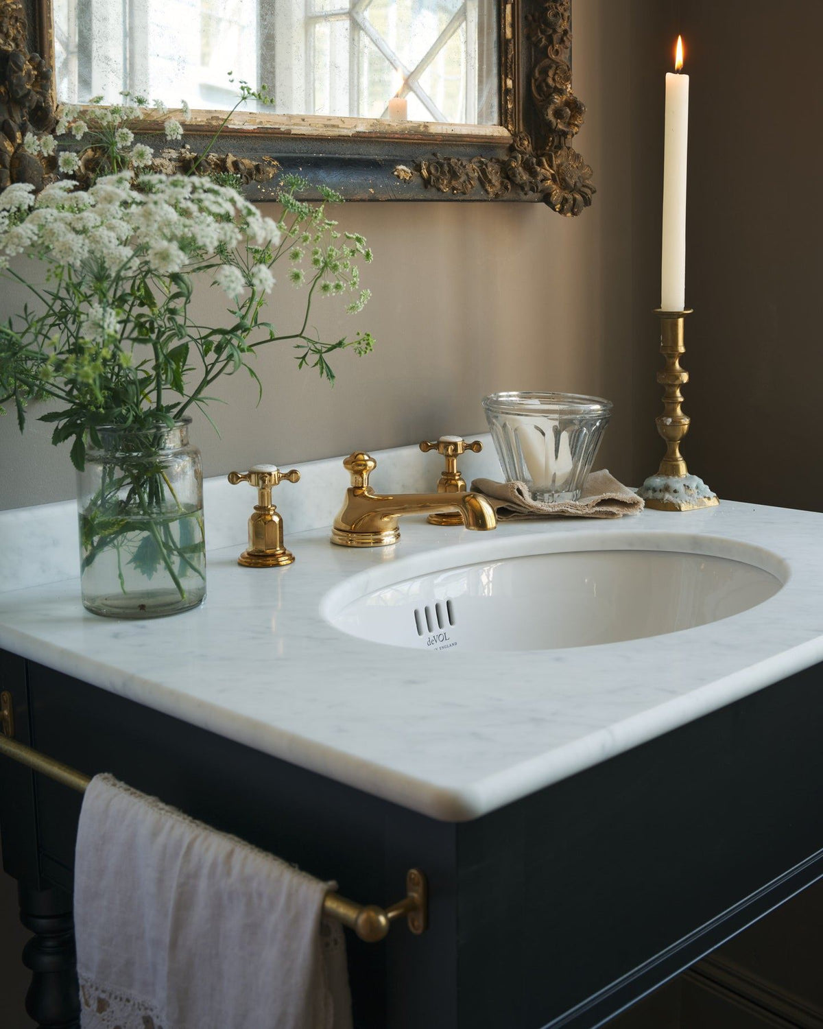 An oblique view of an aged brass mixer tap for a bathroom basin sink fitted to a black painted washstand. TEST