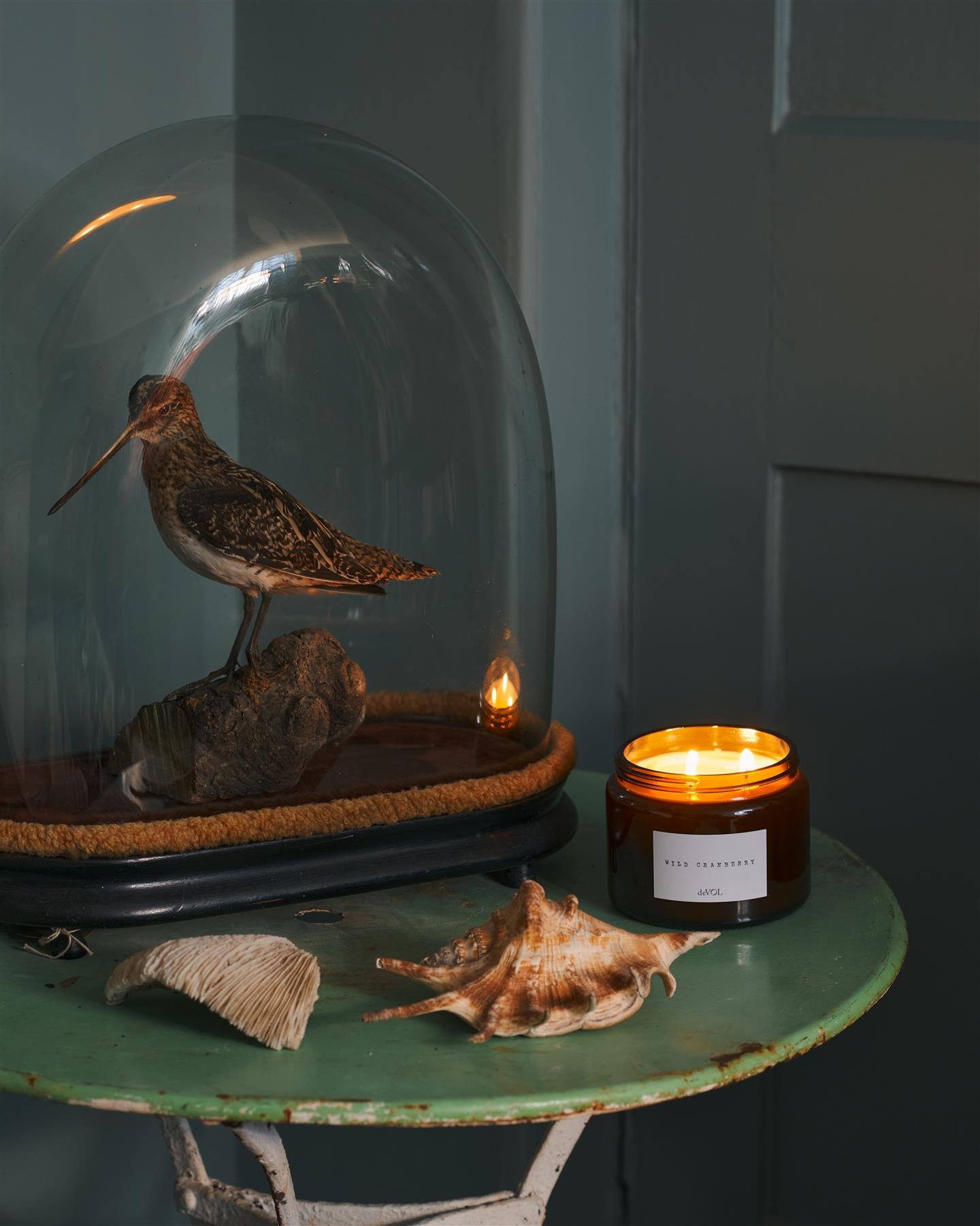 A collection of three lit scented candles in brown glass jars on a polished quartz worktop; small, medium and large.
