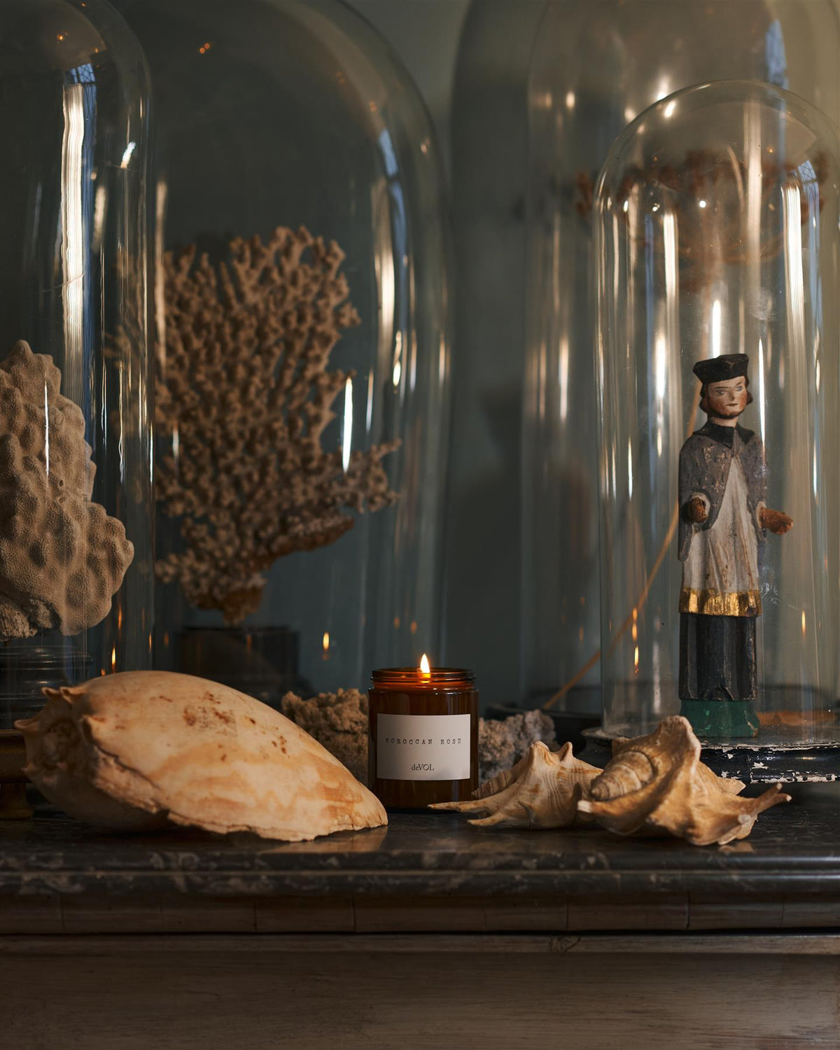 A collection of scented candles in brown glass jars with black lids in a vintage cupboard. TEST