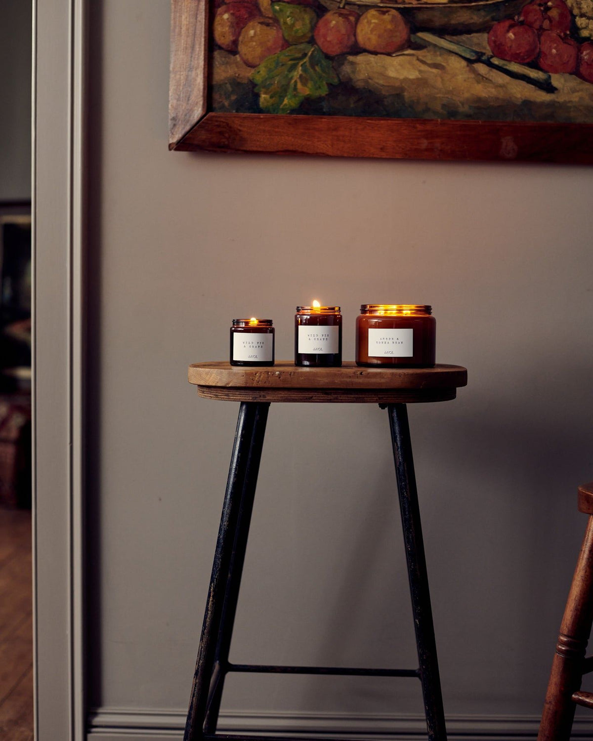 A collection of scented candles in brown glass jars with black lids in a vintage cupboard. TEST