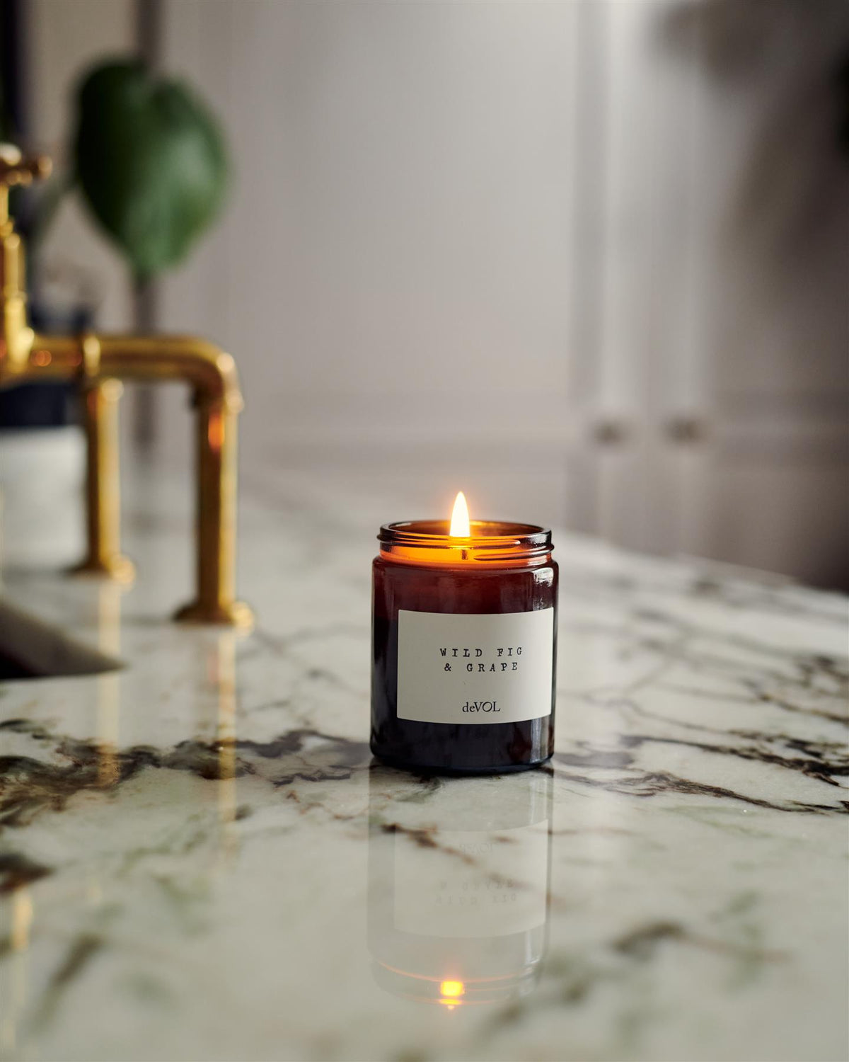 A collection of scented candles in brown glass jars with black lids in a vintage cupboard. TEST