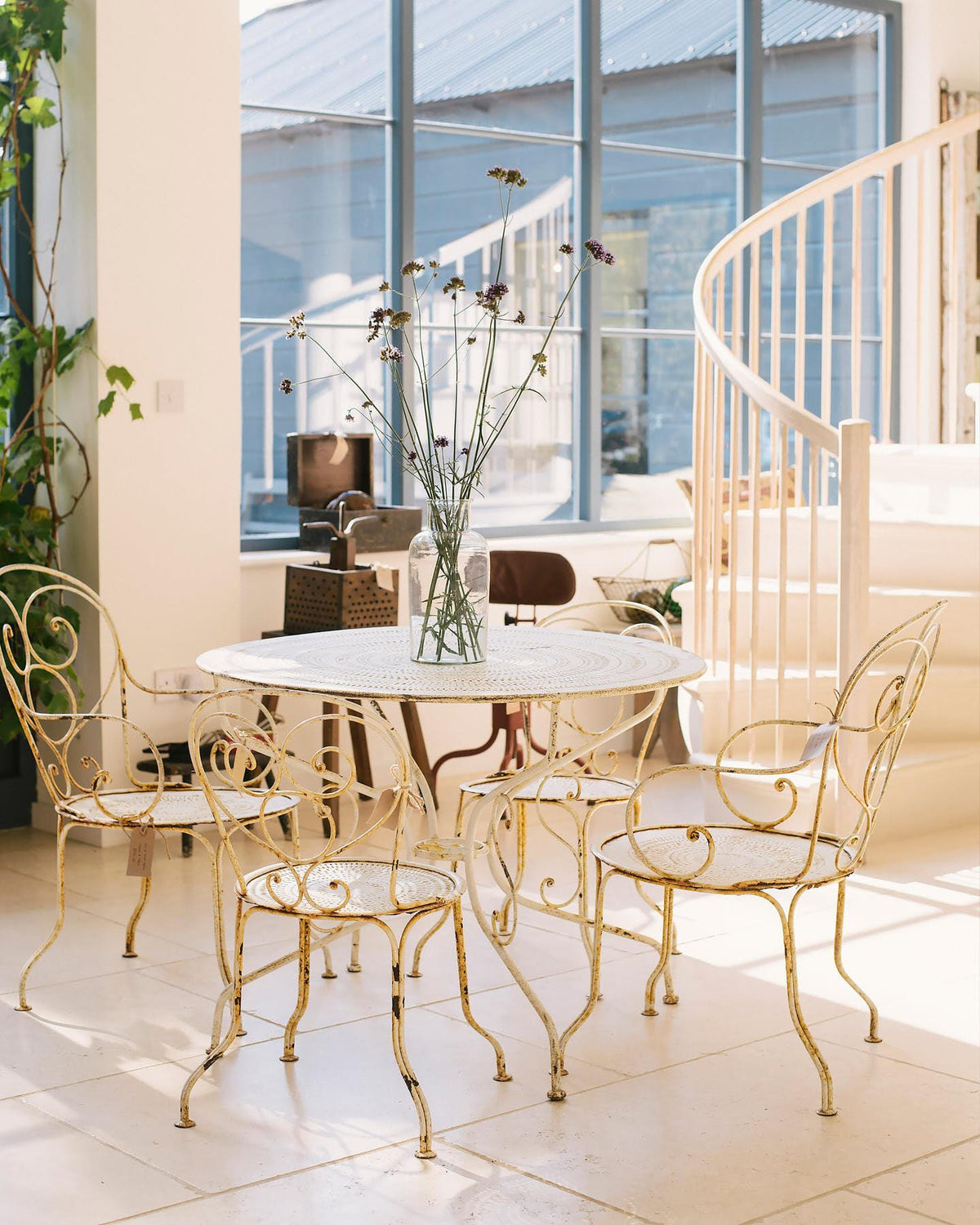 A wide shot looking across deVOL's flooring showroom, with high vaulting ceilings, a unique marble spiral staircase, pale off-white walls and smooth, creamy Light Jerusalem Limestone flooring. TEST