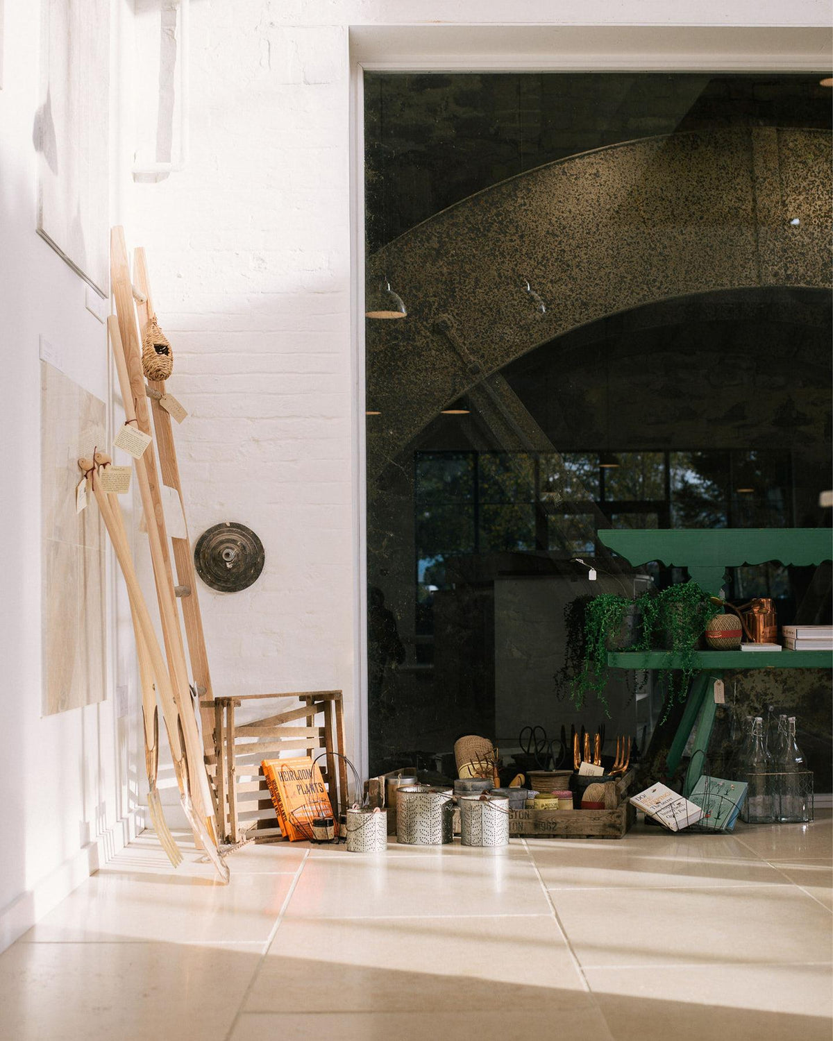 A straight-on shot looking towards the back of deVOL's flooring showroom. Light pours in through the huge glazed windows, casting pools of light and shadows on the wooden staircase and Light Jerusalem Limestone flooring. TEST