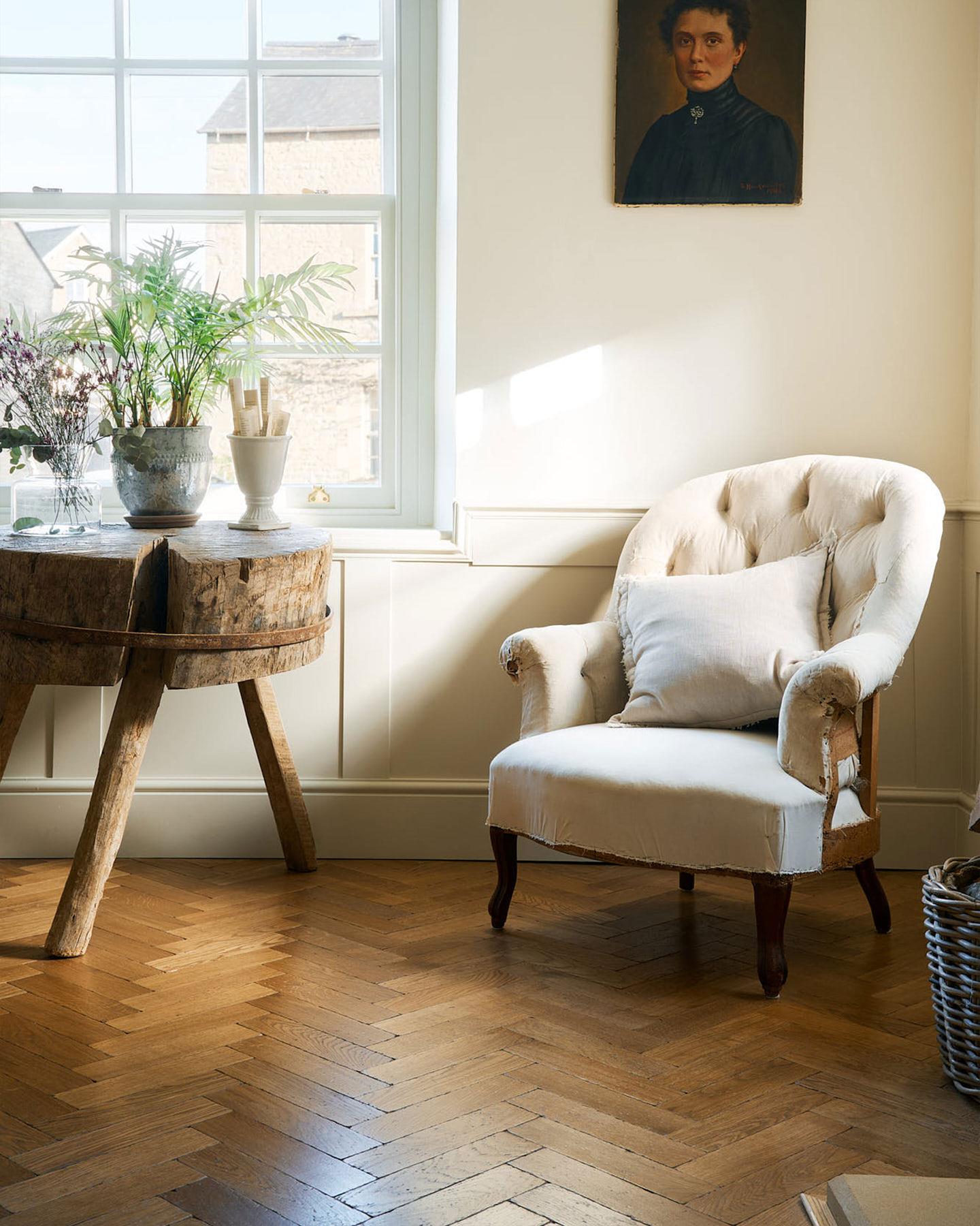 Looking down a hallway with traditional styling, striped wallpaper, white painted woodwork and oak parquet flooring with a warm aged finish.