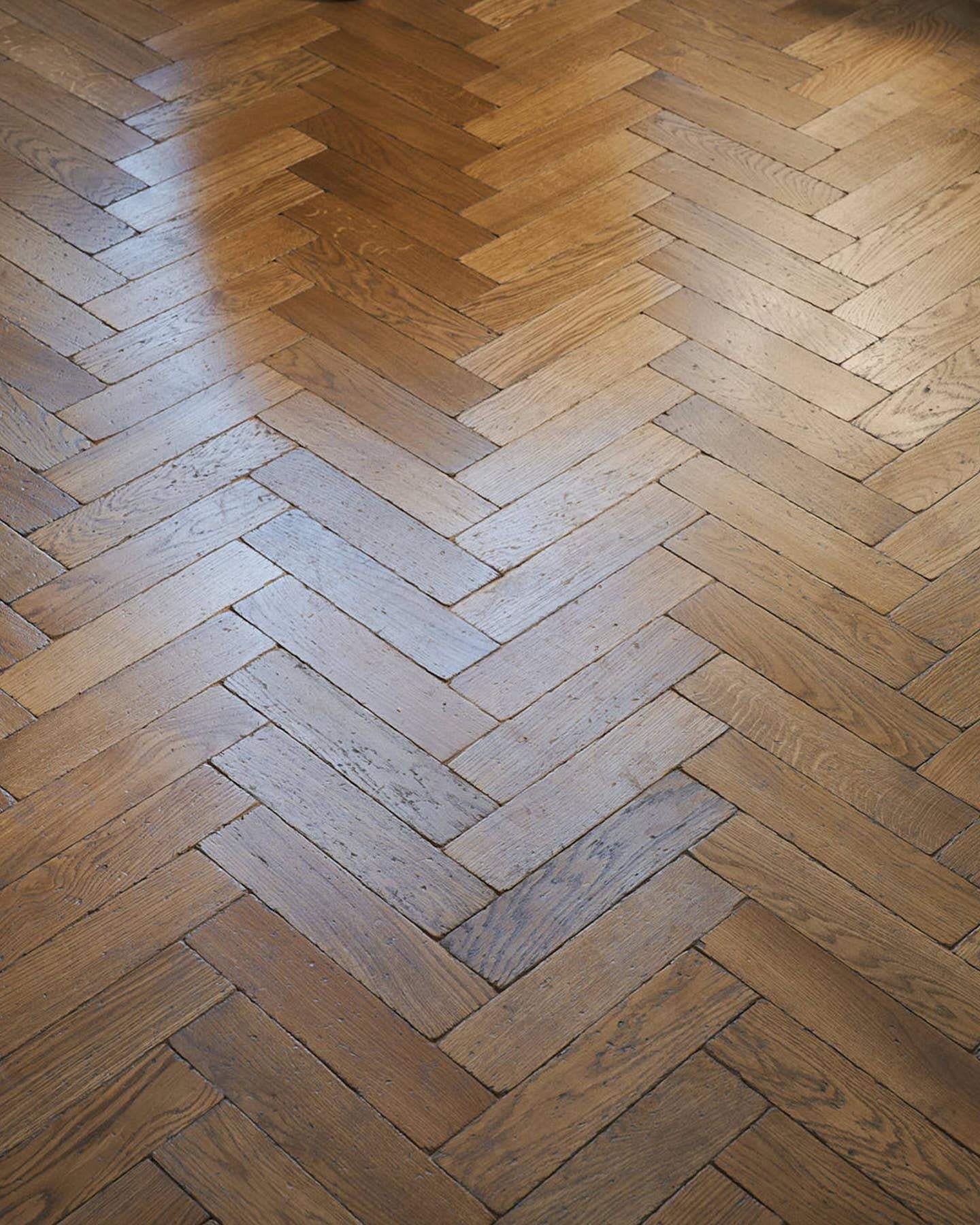 An oblique view of an understairs-doorway with white painted woodwork, vintage brass hardware and oak parquet flooring with a warm aged finish.