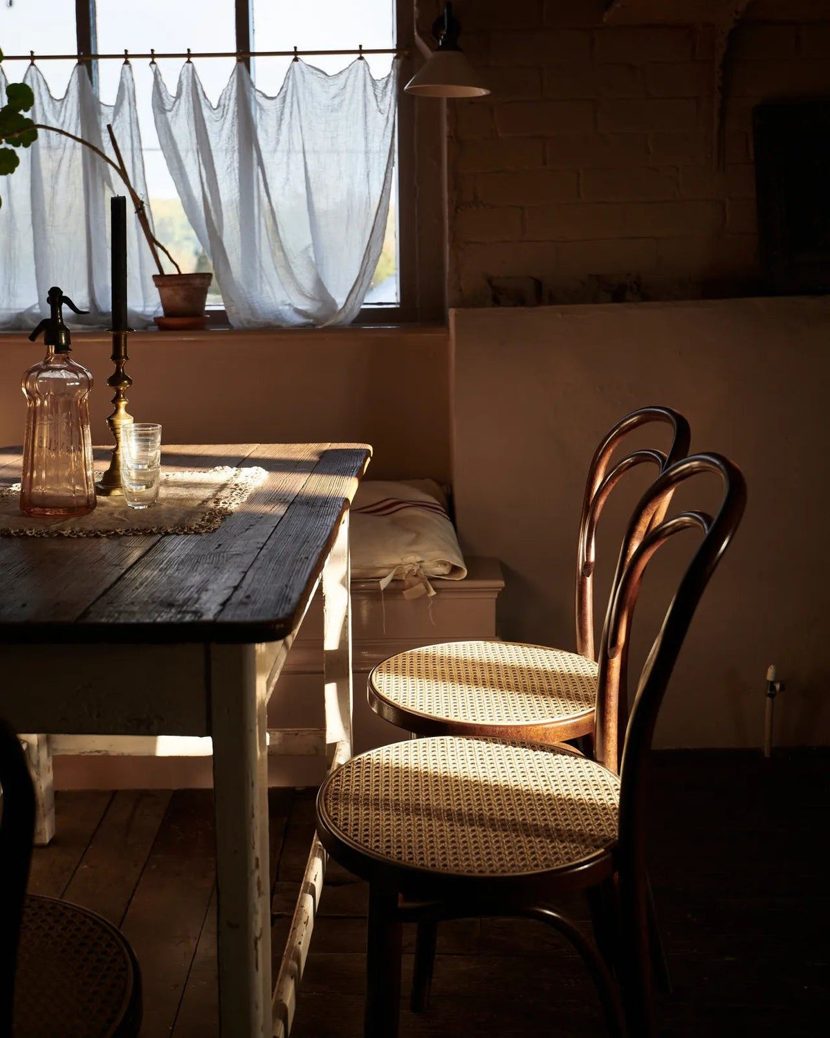 An oblique view of a grand oak prep table with a Carrara marble worktop with a row of cafÈ-style bar stools with dark stained frames and light woven ratten seats. TEST