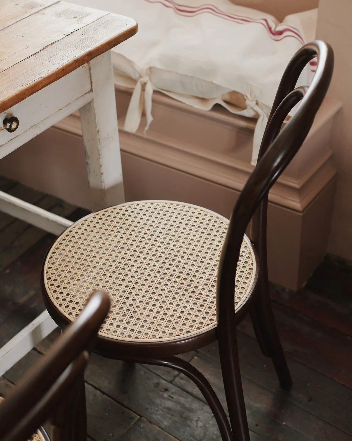 A three-quarters profile view of a cafÈ-style bar stool with a dark stained frame and light woven ratten seat. TEST