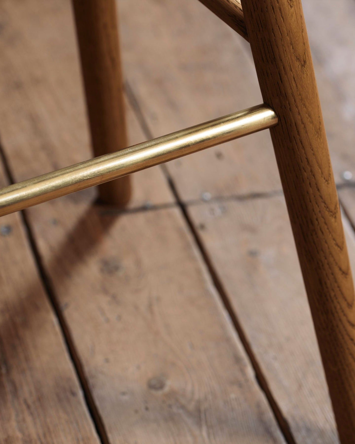 A close-up view of a brass footrail from an oak bar stool. TEST