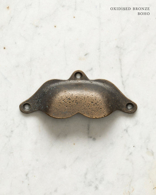 Two bohemian-style cup handles for a kitchen cupboard or drawer with a dark oxidised bronze finish. There is a large and a small size.
