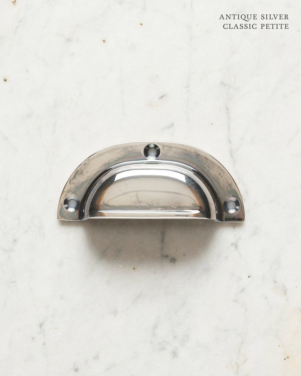 A small classic cup handle for a kitchen cupboard or drawer with a tarnished silver finish. TEST