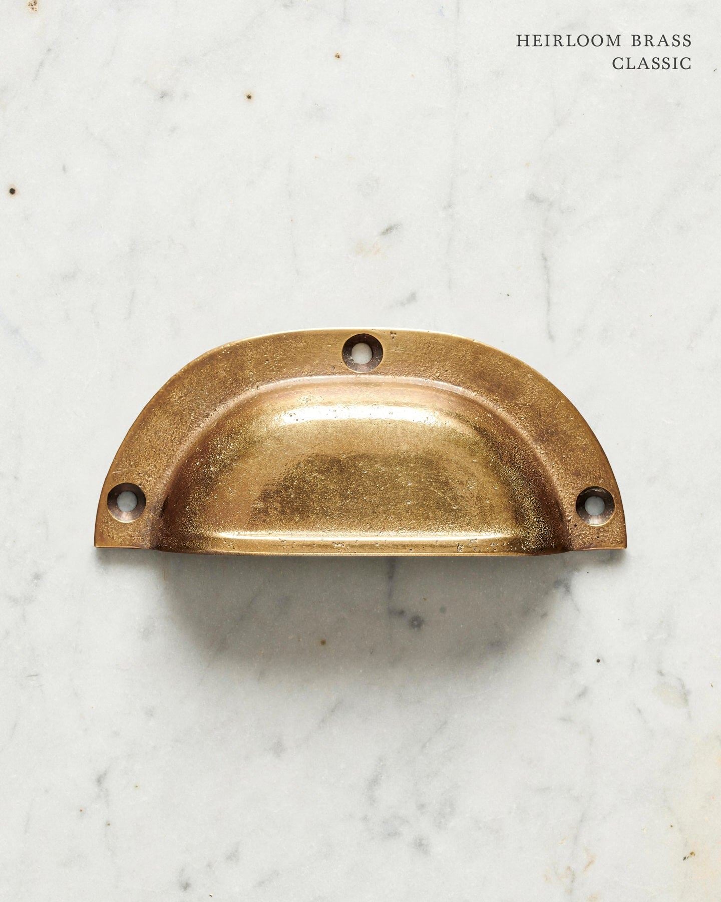 A classic cup handle for a kitchen cupboard or drawer with a warm burnished brass finish.