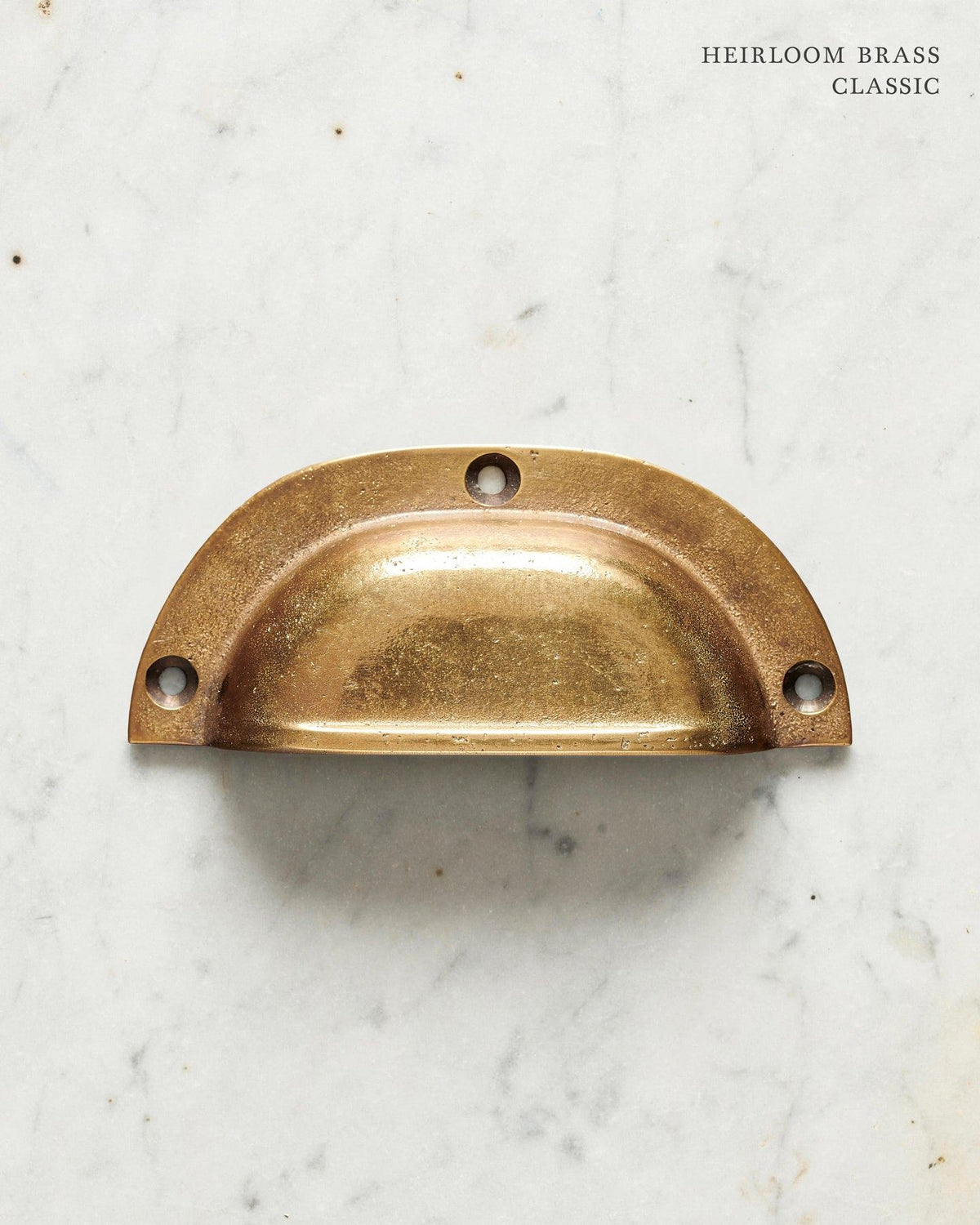 A classic cup handle for a kitchen cupboard or drawer with a warm burnished brass finish. TEST