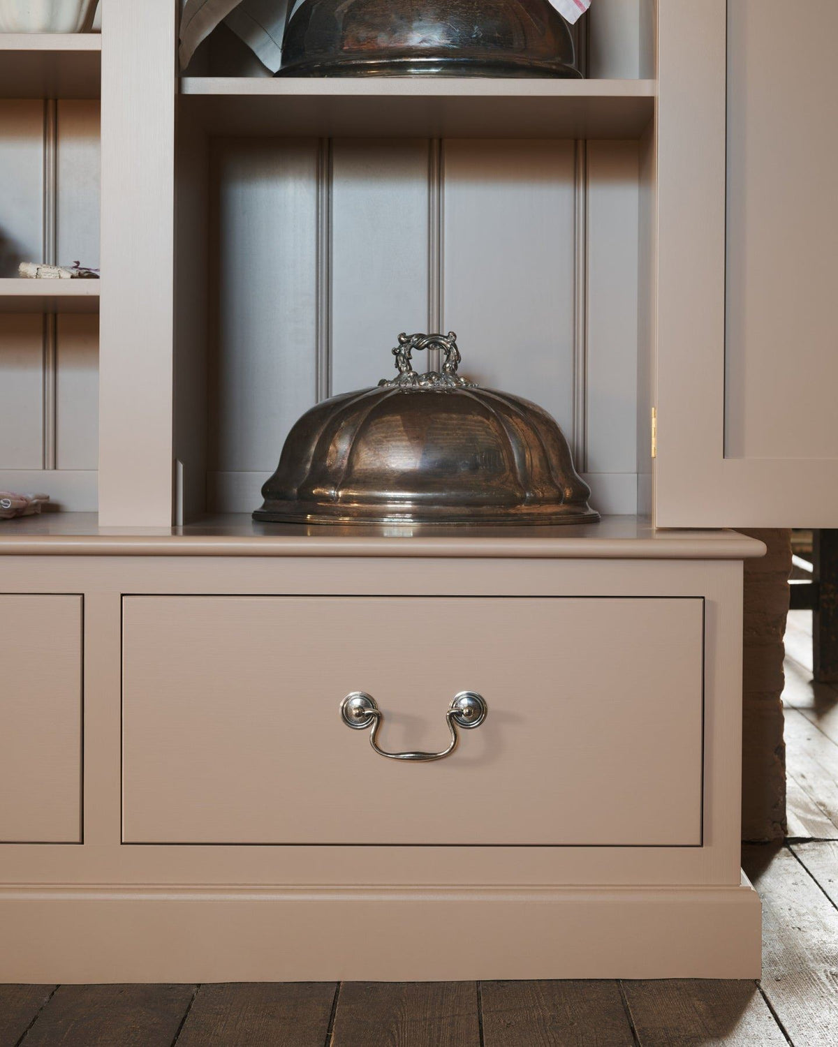 A close-up straight-on view of a dusty pink painted pantry cupboard with bottom drawers, fitted with Georgian-style cup handles in a tarnished 'Bella' silver finish. TEST
