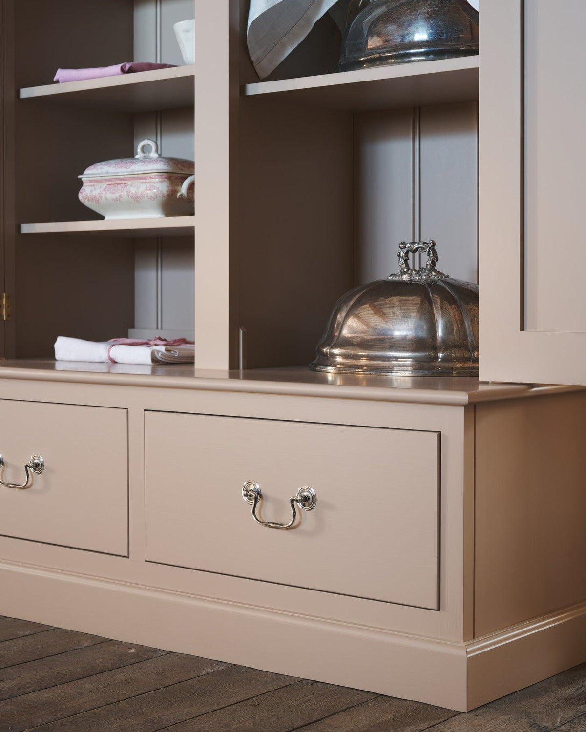 An oblique view of a dusty pink painted pantry cupboard with bottom drawers, fitted with Georgian-style cup handles in a tarnished 'Bella' silver finish. TEST