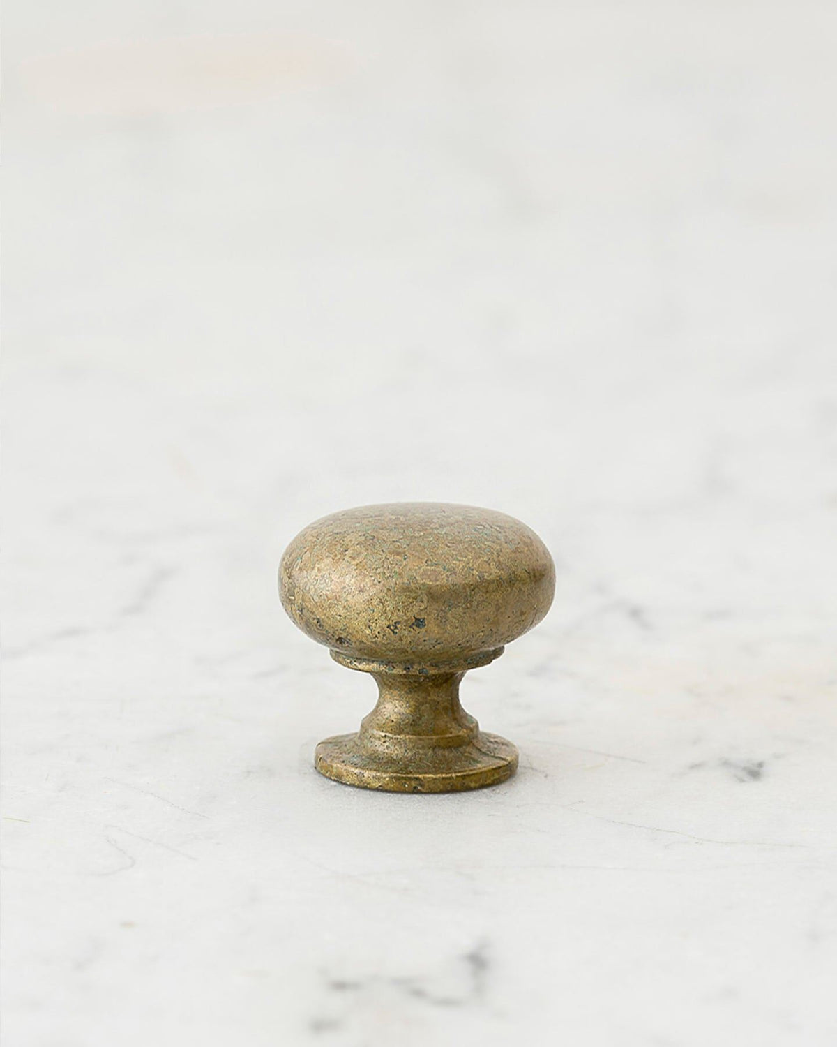 A 'Petite' classic knob for a kitchen cupboard or drawer with an aged verdigris brass finish and unique dented textures as if was made by an artisan blacksmith centuries ago. TEST