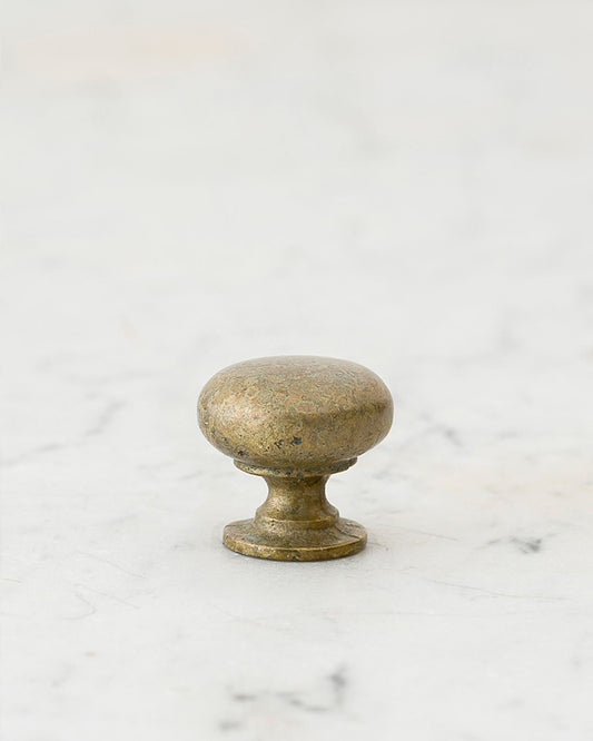 A 'Petite' classic knob for a kitchen cupboard or drawer with an aged verdigris brass finish and unique dented textures as if was made by an artisan blacksmith centuries ago.