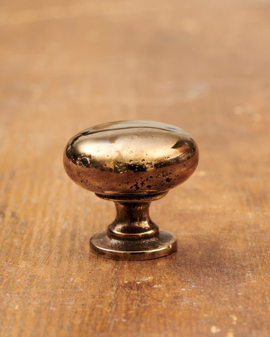 A 'Medium' classic knob for a kitchen cupboard or drawer with a warm burnished brass finish and unique dented textures as if was made by an artisan blacksmith centuries ago.