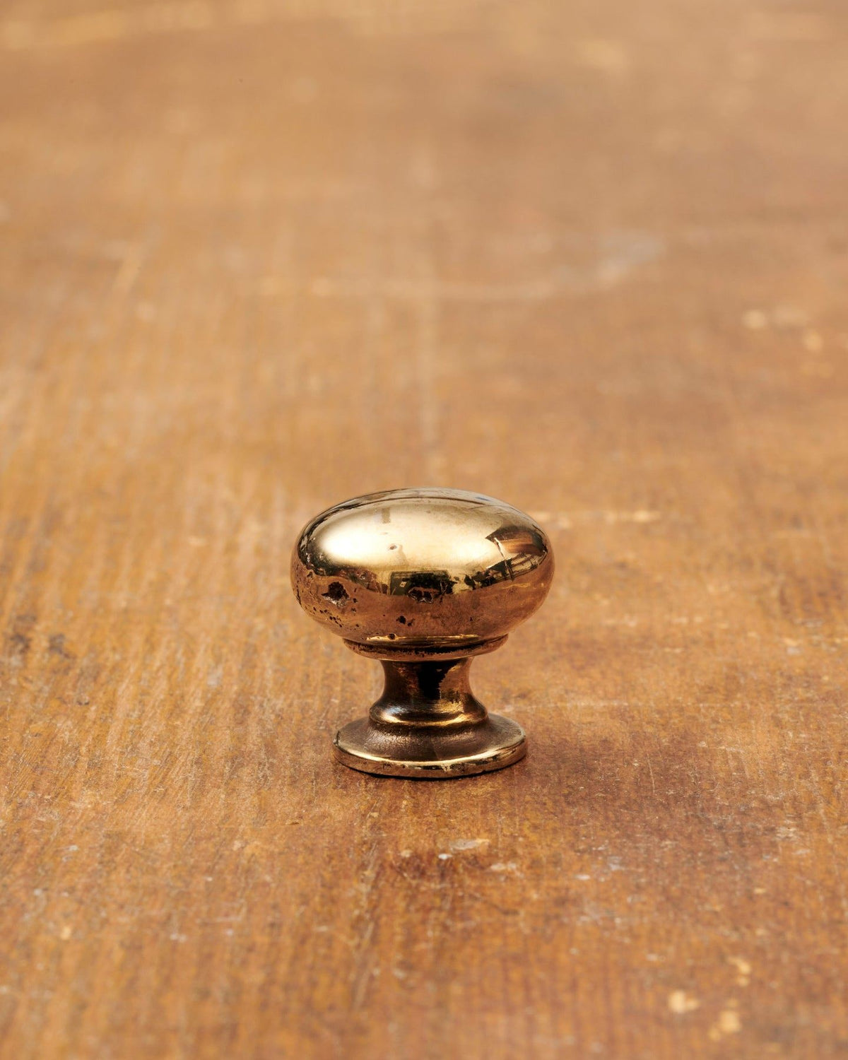 A 'Petite' classic knob for a kitchen cupboard or drawer with a warm burnished brass finish and unique dented textures as if was made by an artisan blacksmith centuries ago. TEST