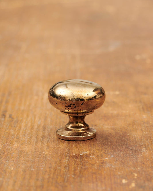 A 'Small' classic knob for a kitchen cupboard or drawer with a warm burnished brass finish and unique dented textures as if was made by an artisan blacksmith centuries ago.