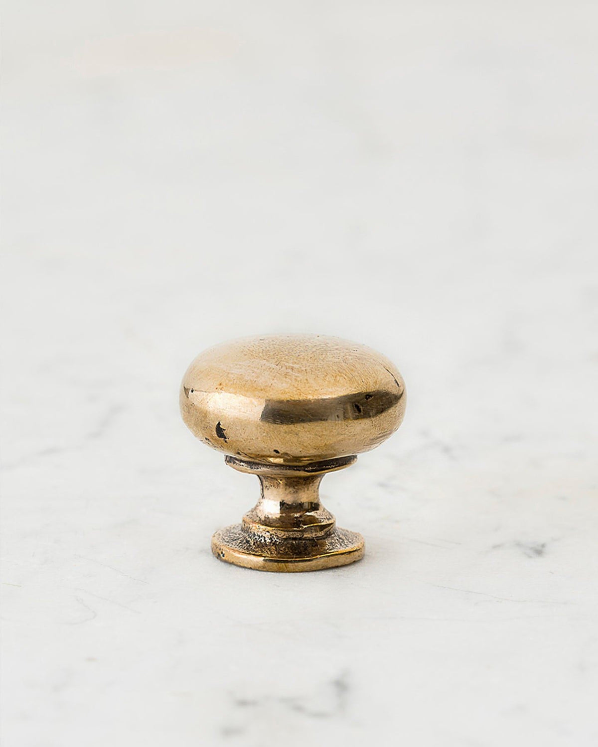 A 'Small' classic knob for a kitchen cupboard or drawer with a bright polished bronze finish and unique dented textures that makes it look like a beloved, well aged bronze from centuries ago. TEST